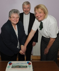 Canon Ken McReynolds looks on as Pat Harvey and Sister Myrtle Morrison cut the 10th anniversary cake.